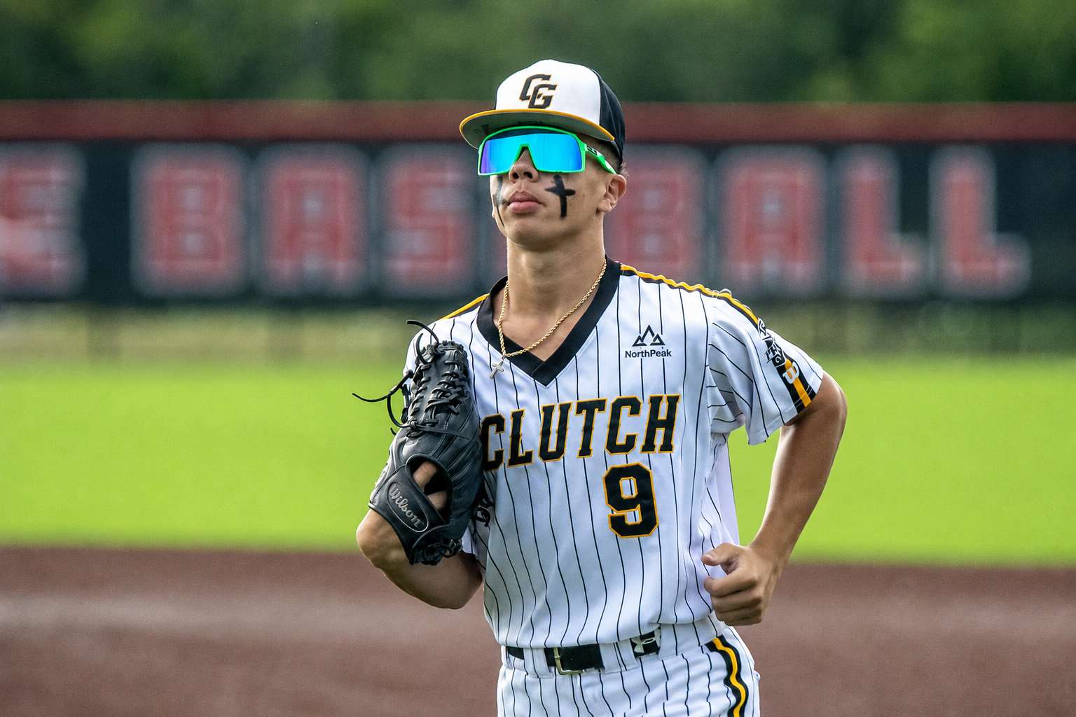 Youth baseball player in a pinstriped jersey with a sponsor patch on the sleeve